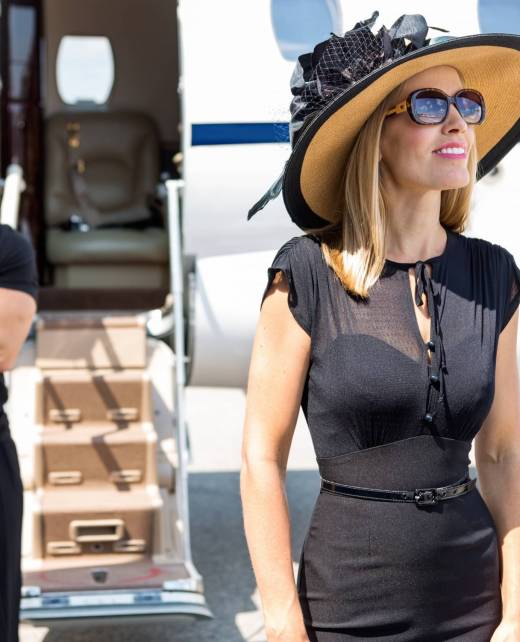Happy Woman With Bodyguard And Private Jet In Background Happy woman wearing sunhat and sunglasses with bodyguard and private jet in background